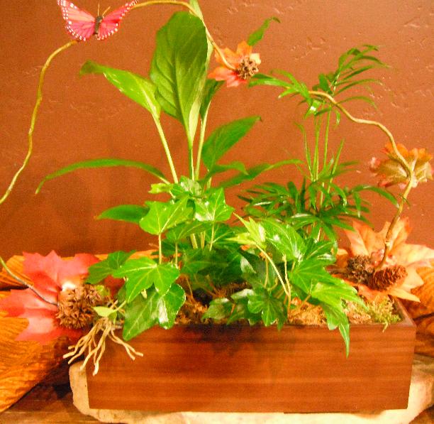 Potted arrangement with green ivy and orange flowers in a wooden planter