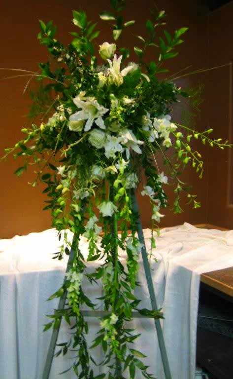 Tall white floral spray on a stand with cascading greenery