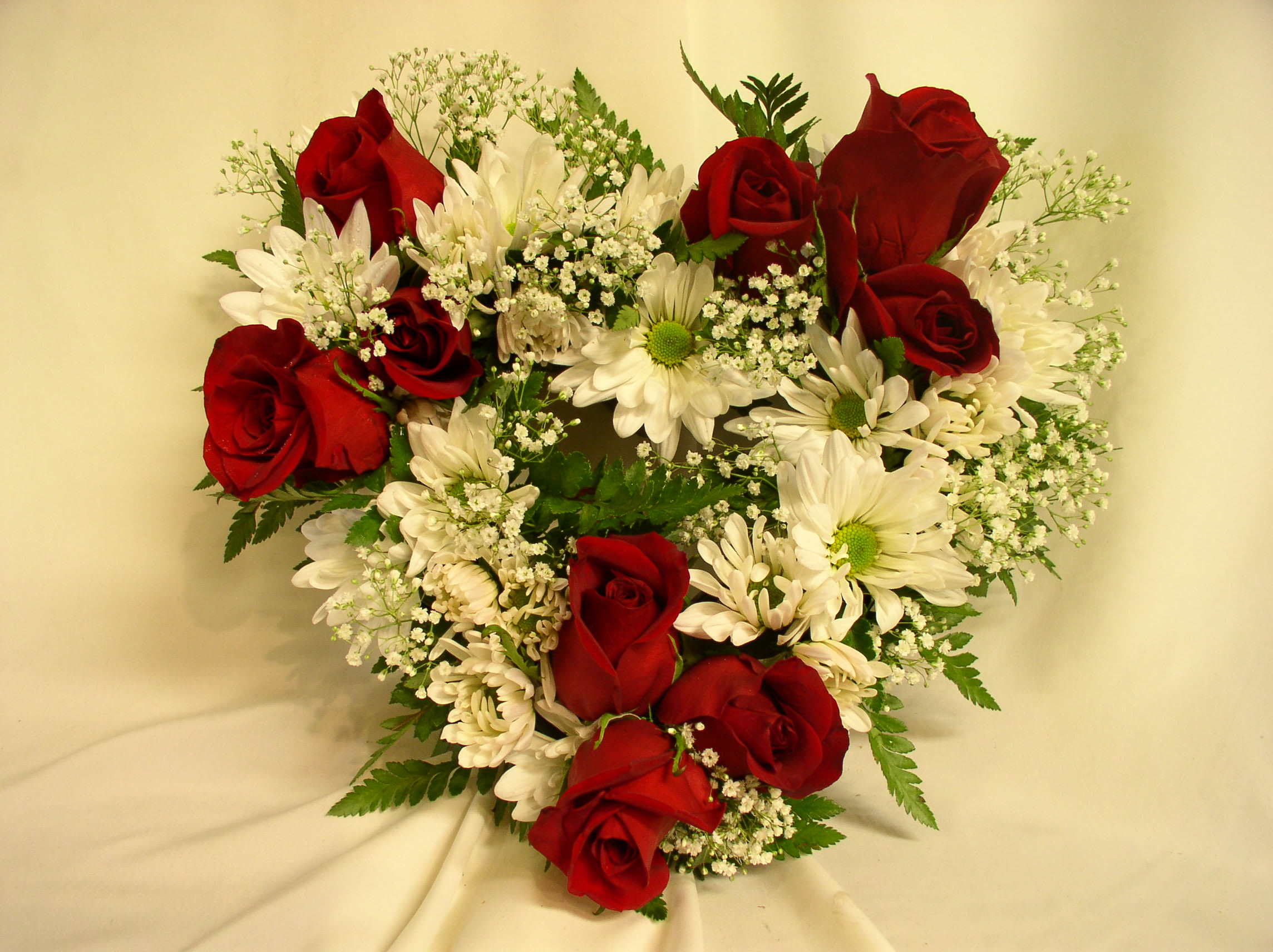 Heart-shaped bouquet of red roses and white daisies
