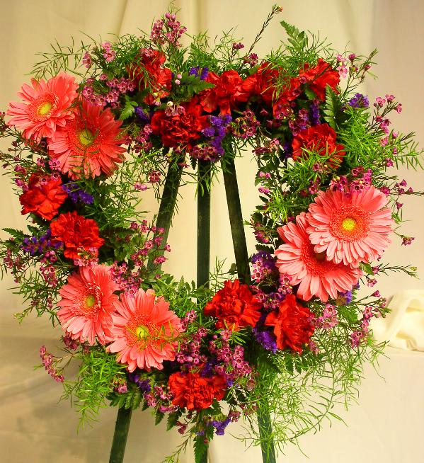 Heart-shaped floral wreath with pink gerbera daisies and red carnations