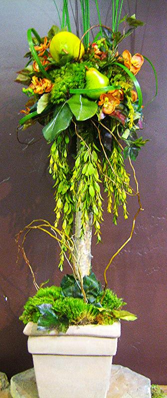 Tall floral topiary with green fruit accents in a white planter
