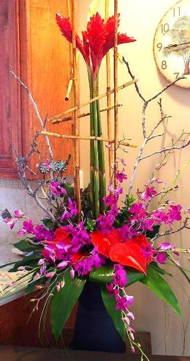 Tall red and purple floral arrangement in a dark vase