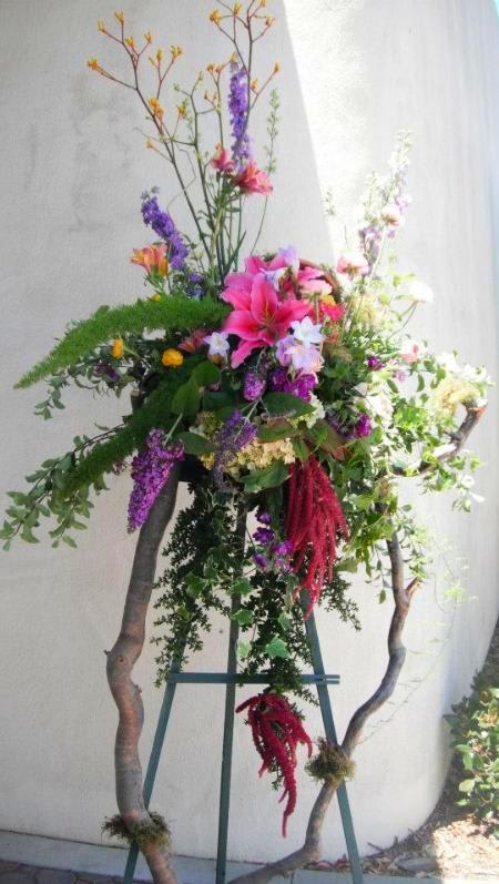 Tall floral arrangement with pink lilies and purple blooms on a stand