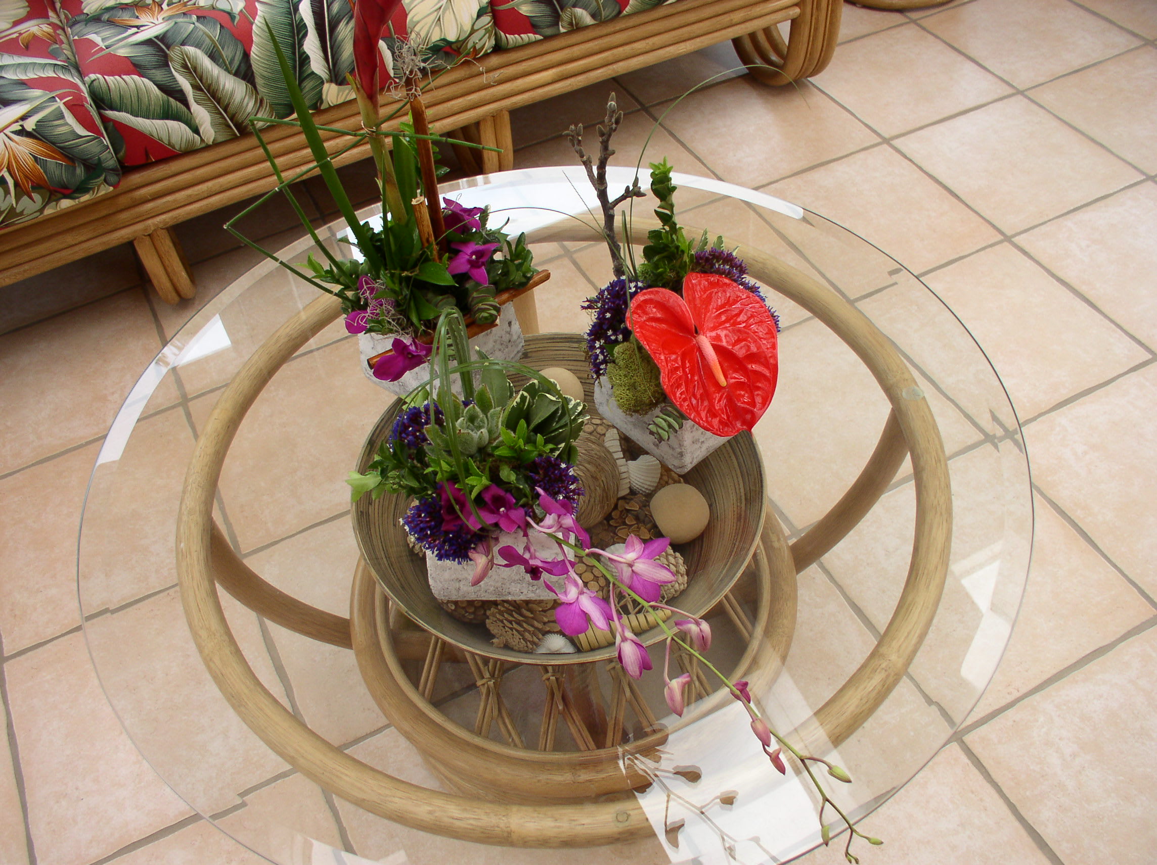 Three tropical floral arrangements on a glass table