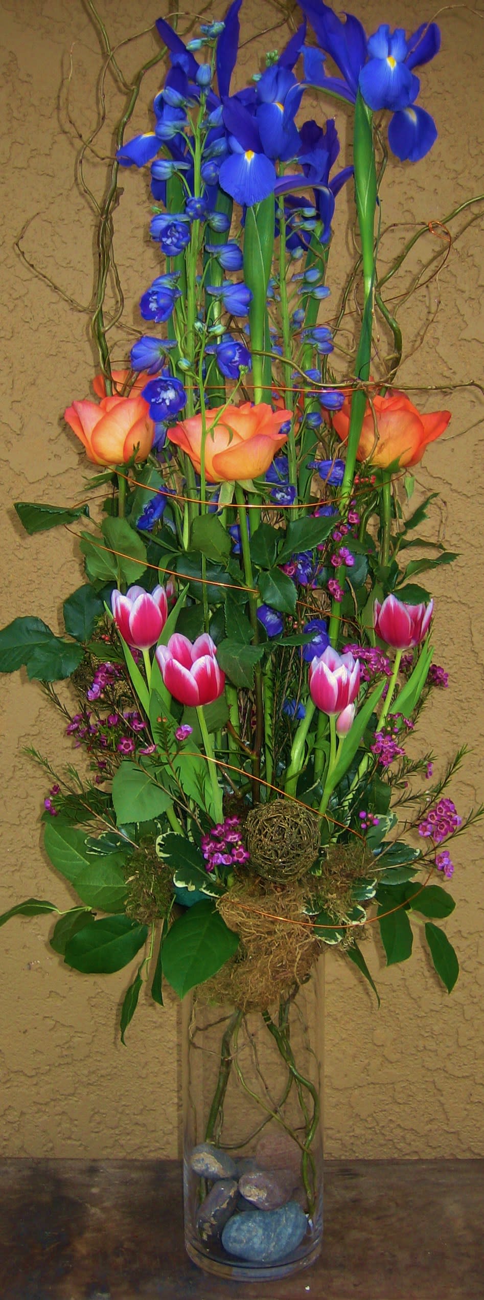 Tall bouquet of blue irises and pink tulips in a glass vase