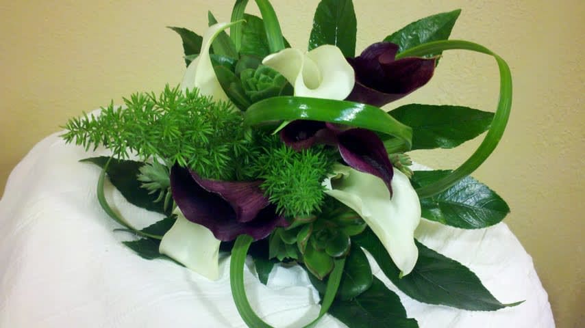 Bouquet of white and dark purple calla lilies with green foliage