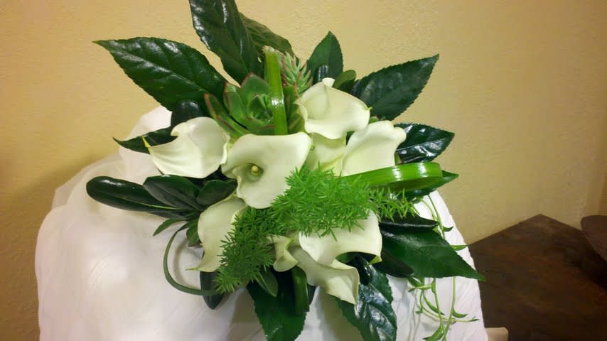 White calla lilies with dark green foliage in a bouquet