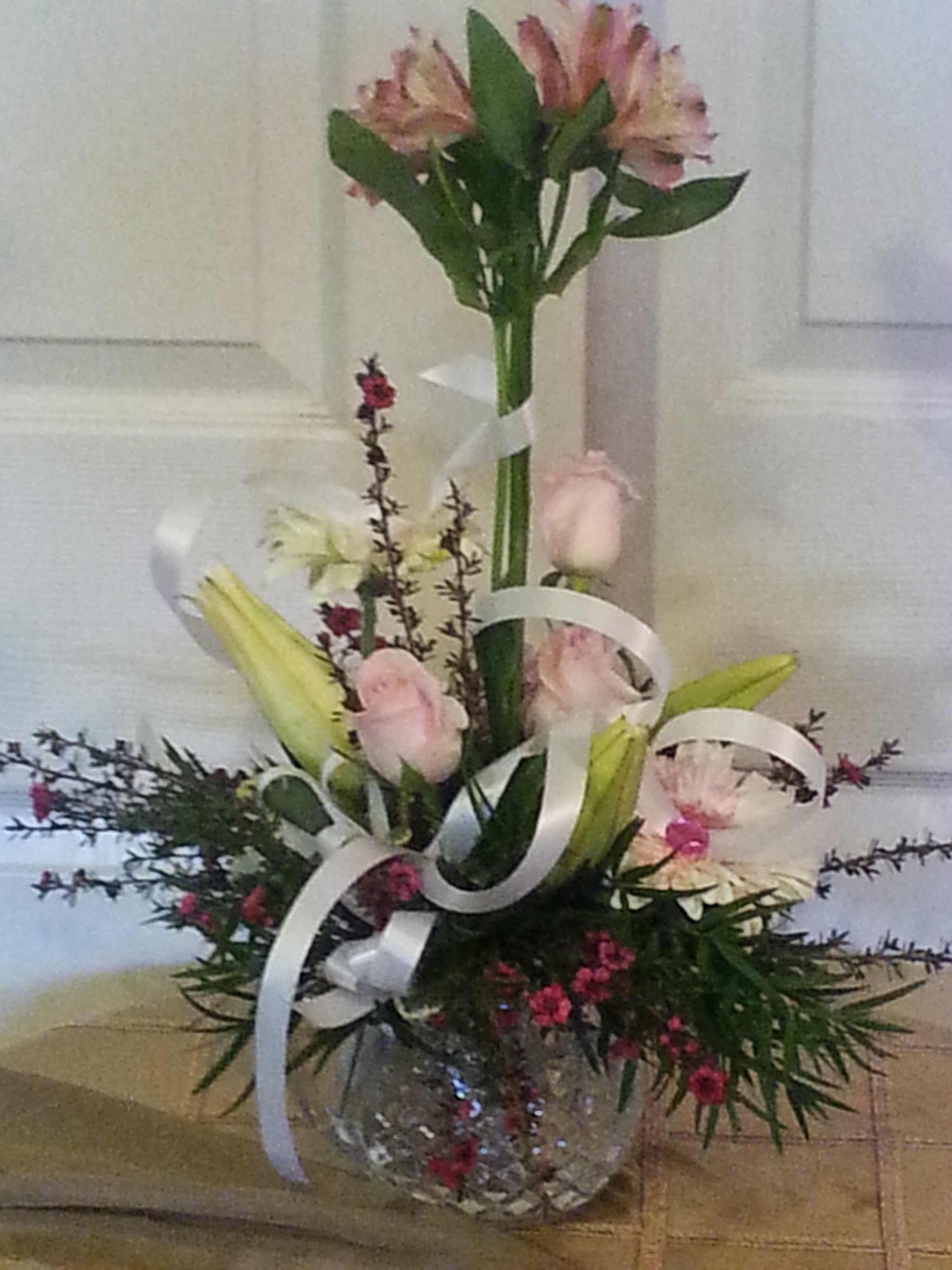 Tall mixed bouquet with pink lilies and roses in a glass vase