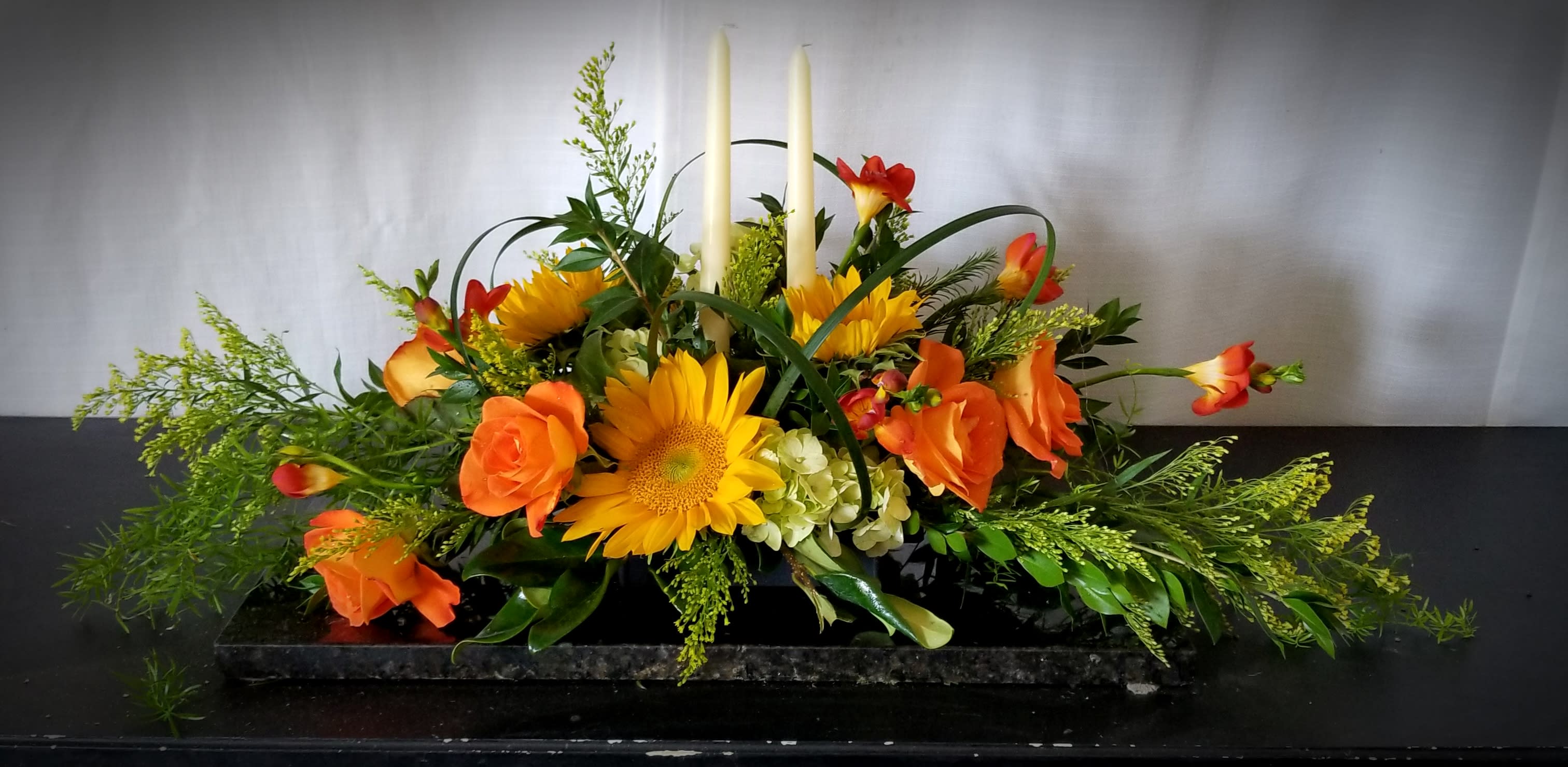 Orange and yellow floral centerpiece with tall white candles