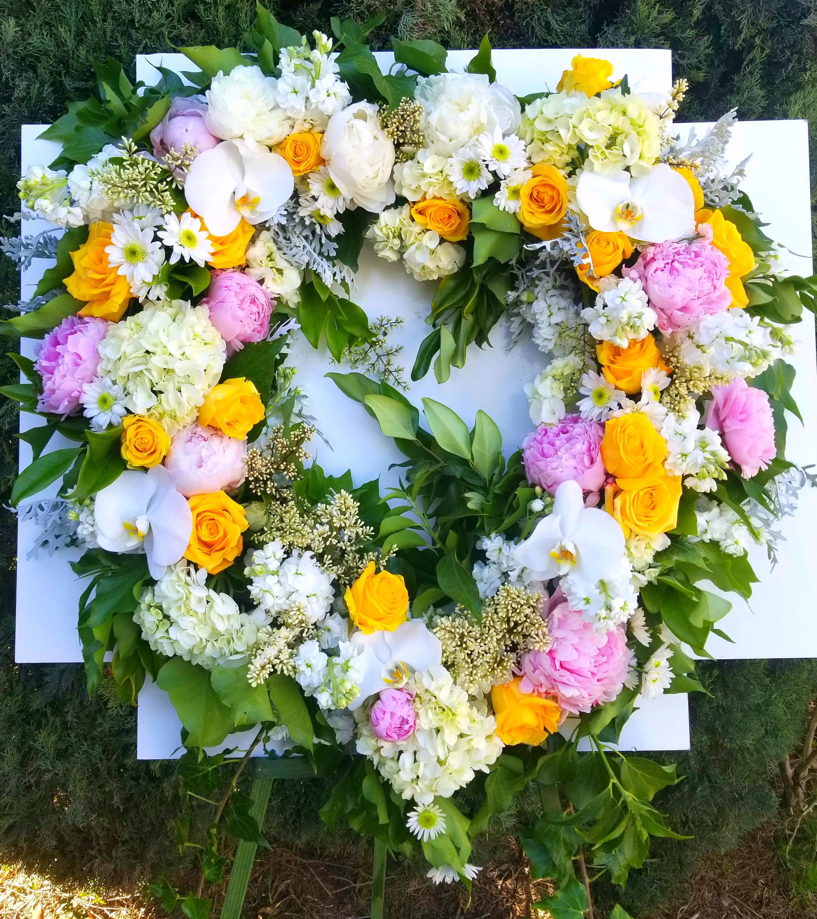 Heart-shaped floral wreath with white, pink, and yellow blooms