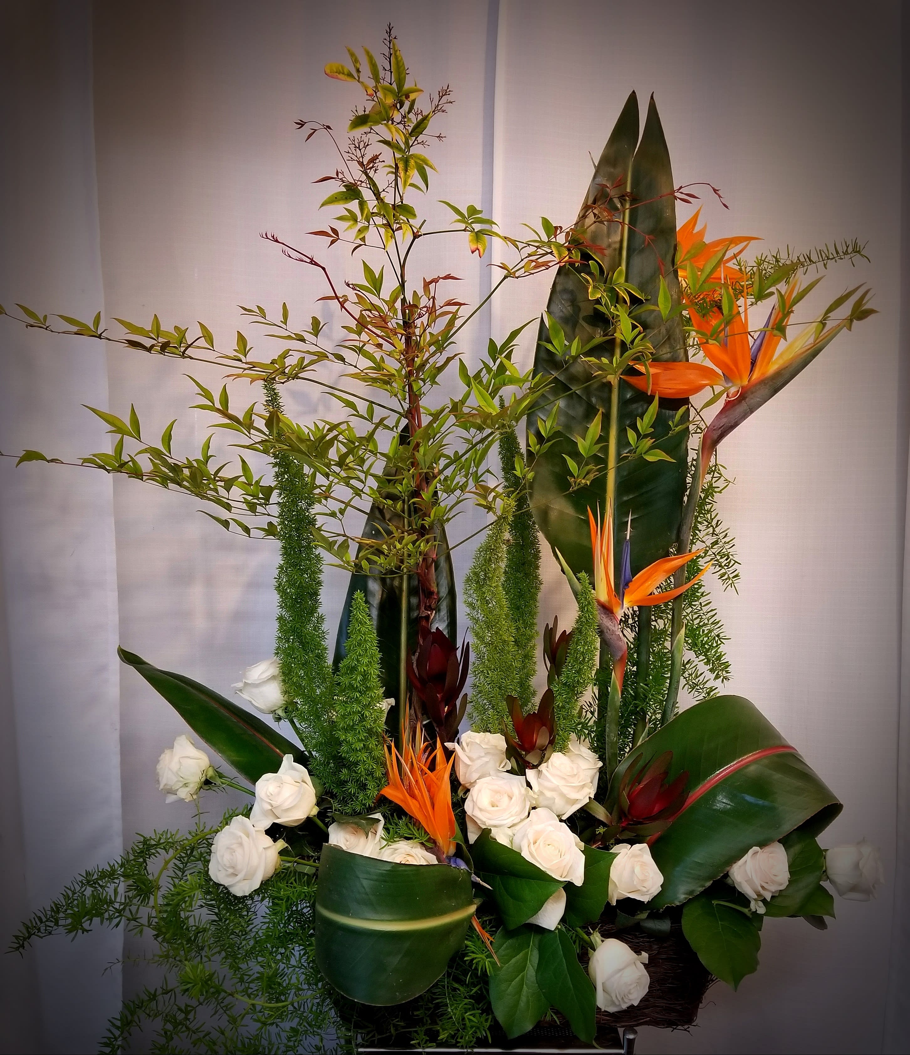 Tall tropical arrangement with white roses and orange bird-of-paradise flowers