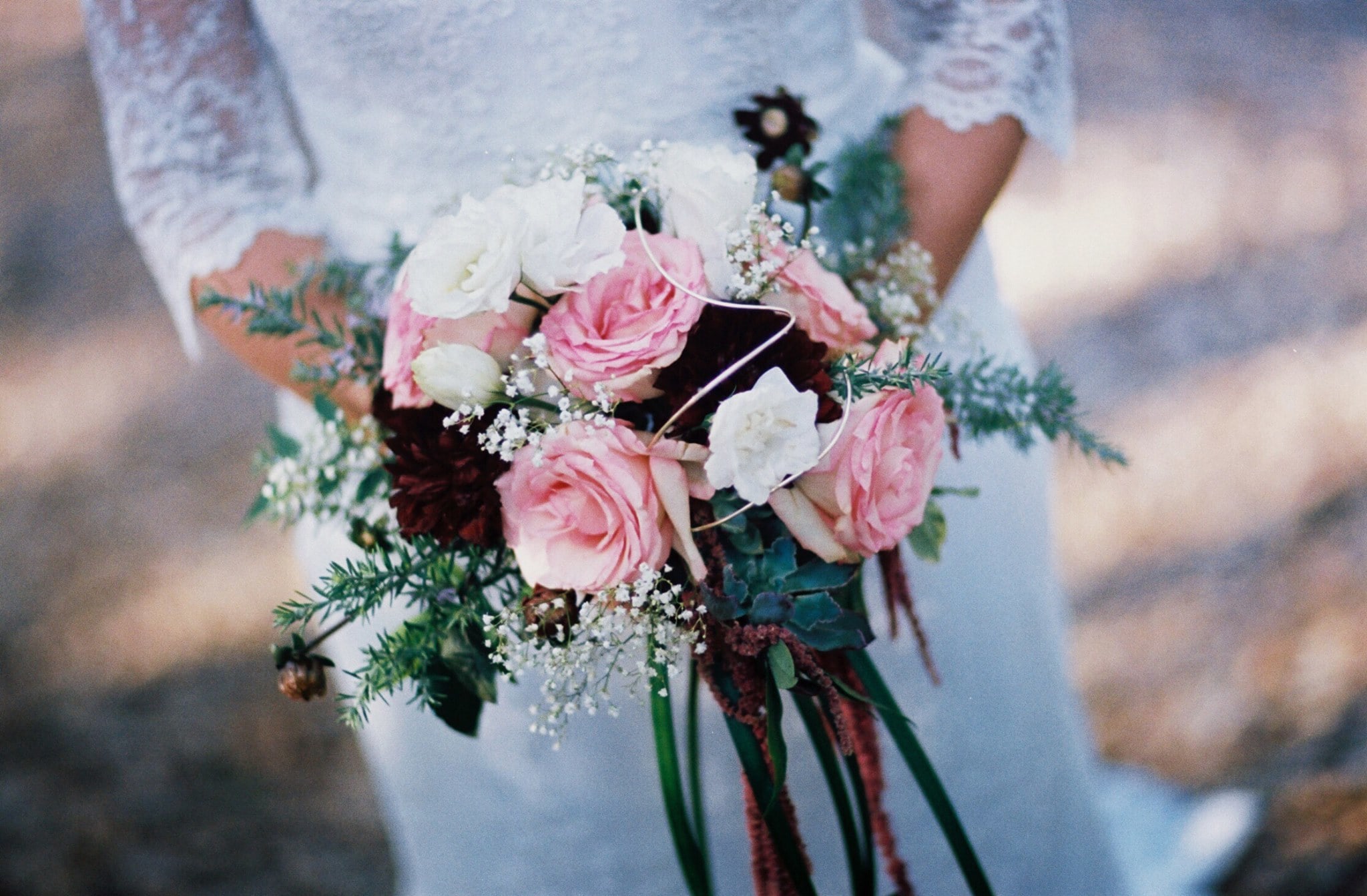 Bride holding a bouquet of pink and white roses with greenery