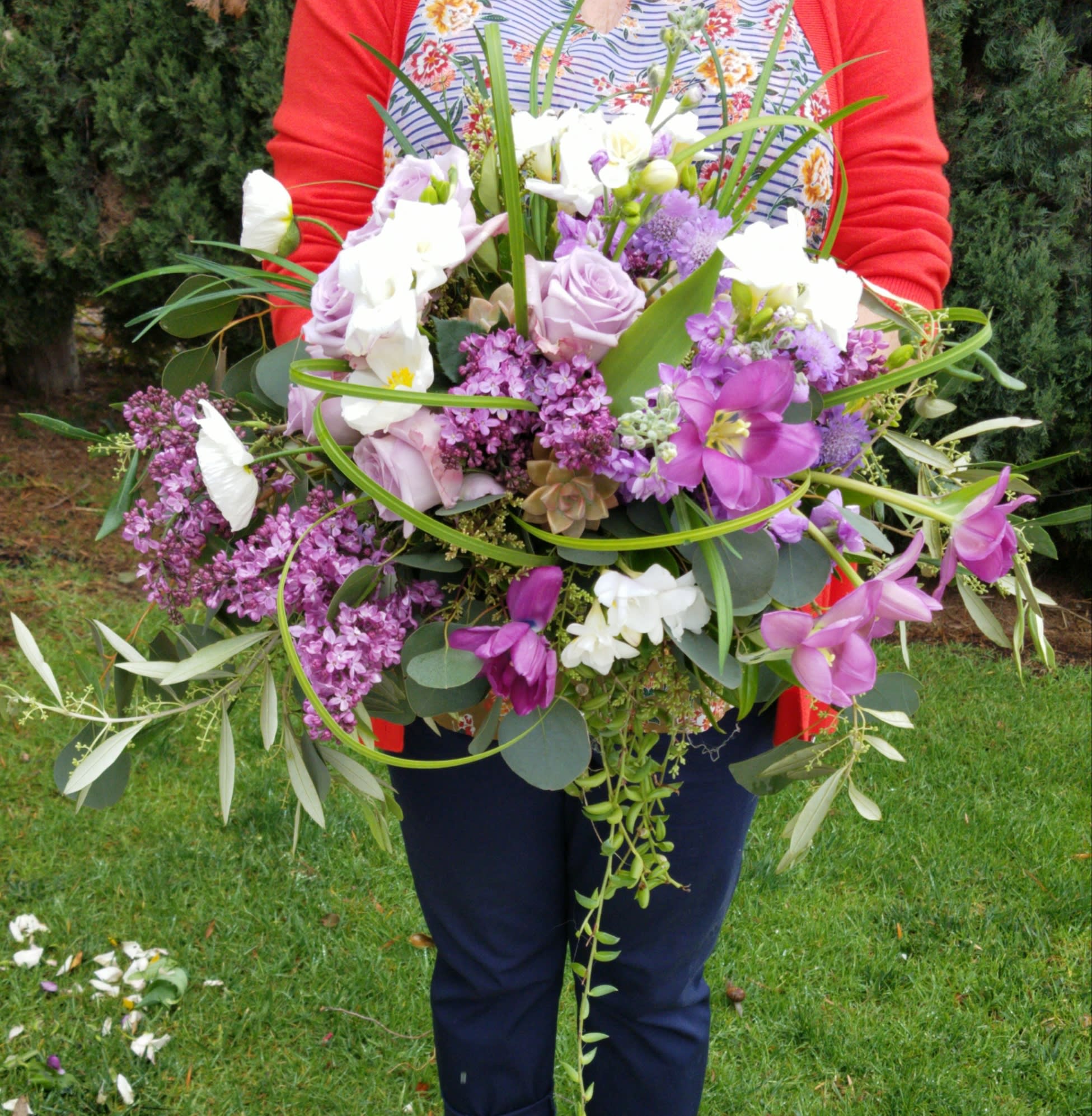 Large bouquet of purple and white flowers held outdoors