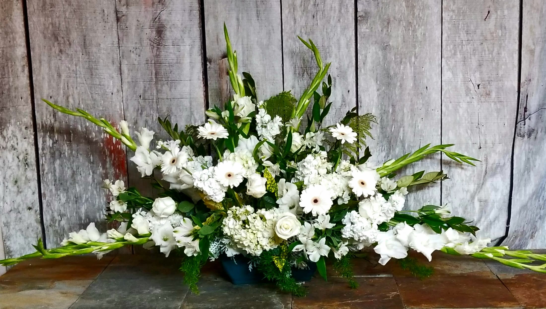 Large white floral arrangement with long green spikes in a low container