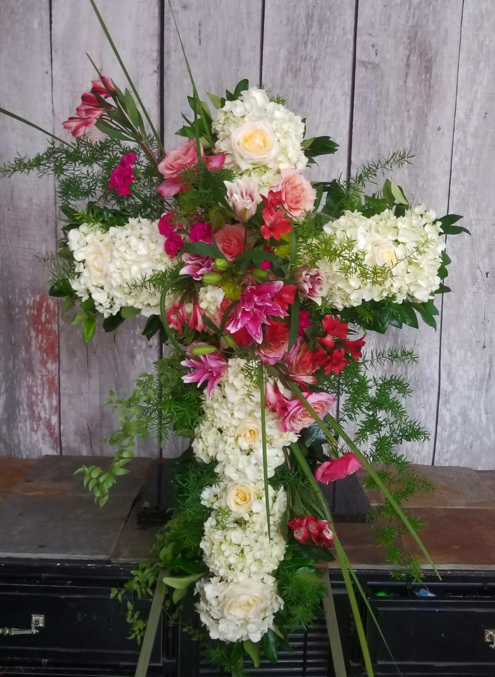 Cross-shaped floral arrangement with white hydrangeas and pink flowers