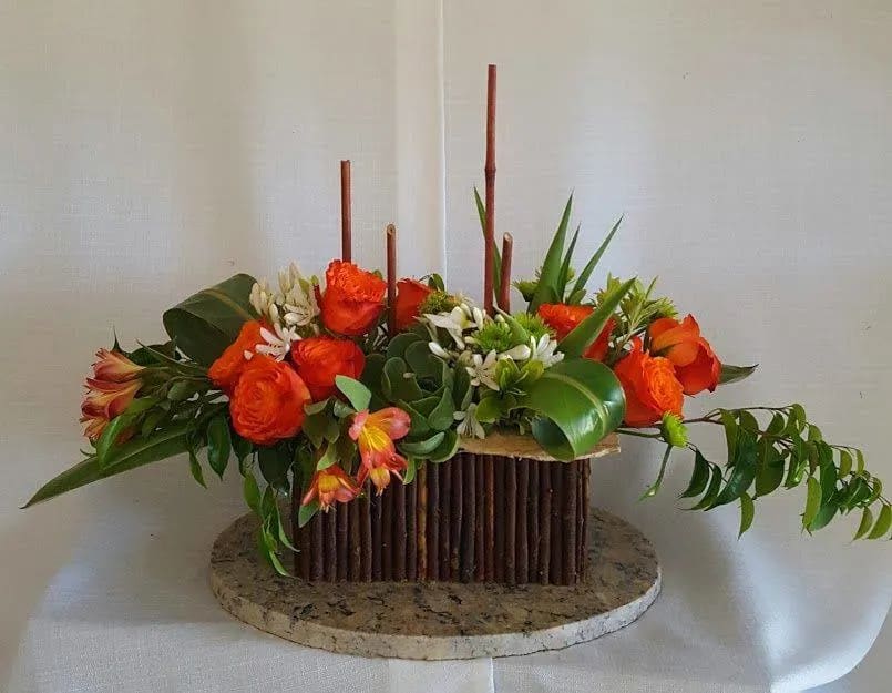 Orange roses arranged in a low rectangular centerpiece with greenery