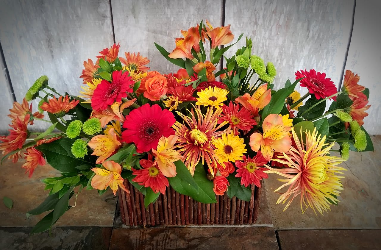 Bright mixed flower arrangement in a rectangular wooden basket