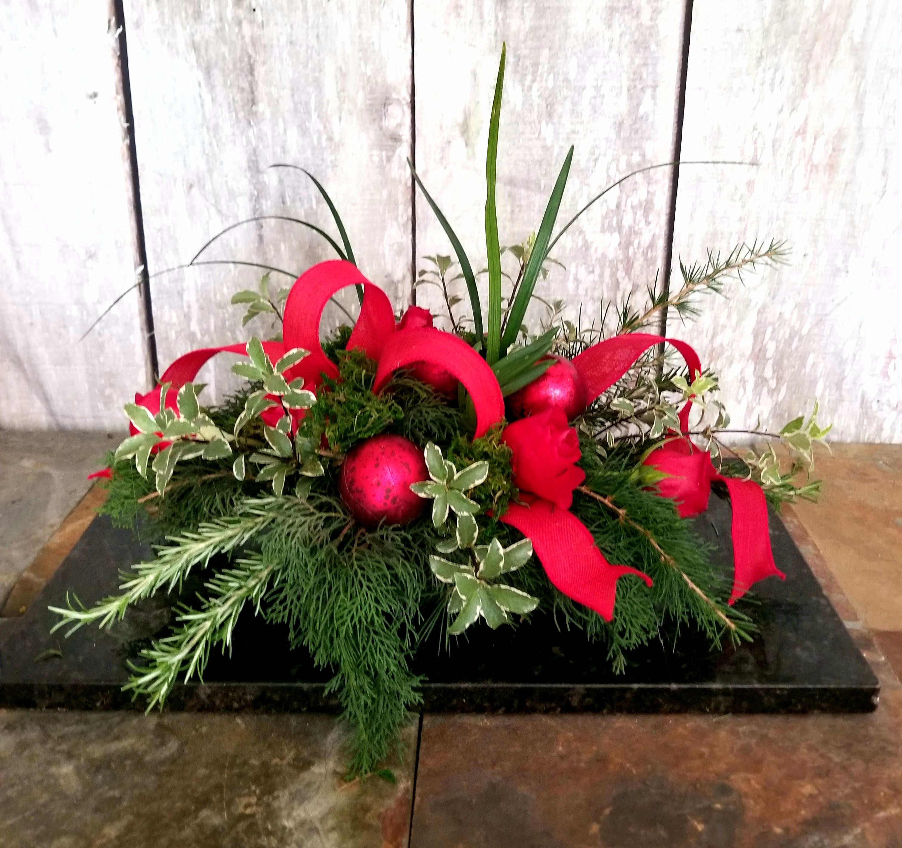 Low holiday arrangement with red ribbon loops and red ornaments