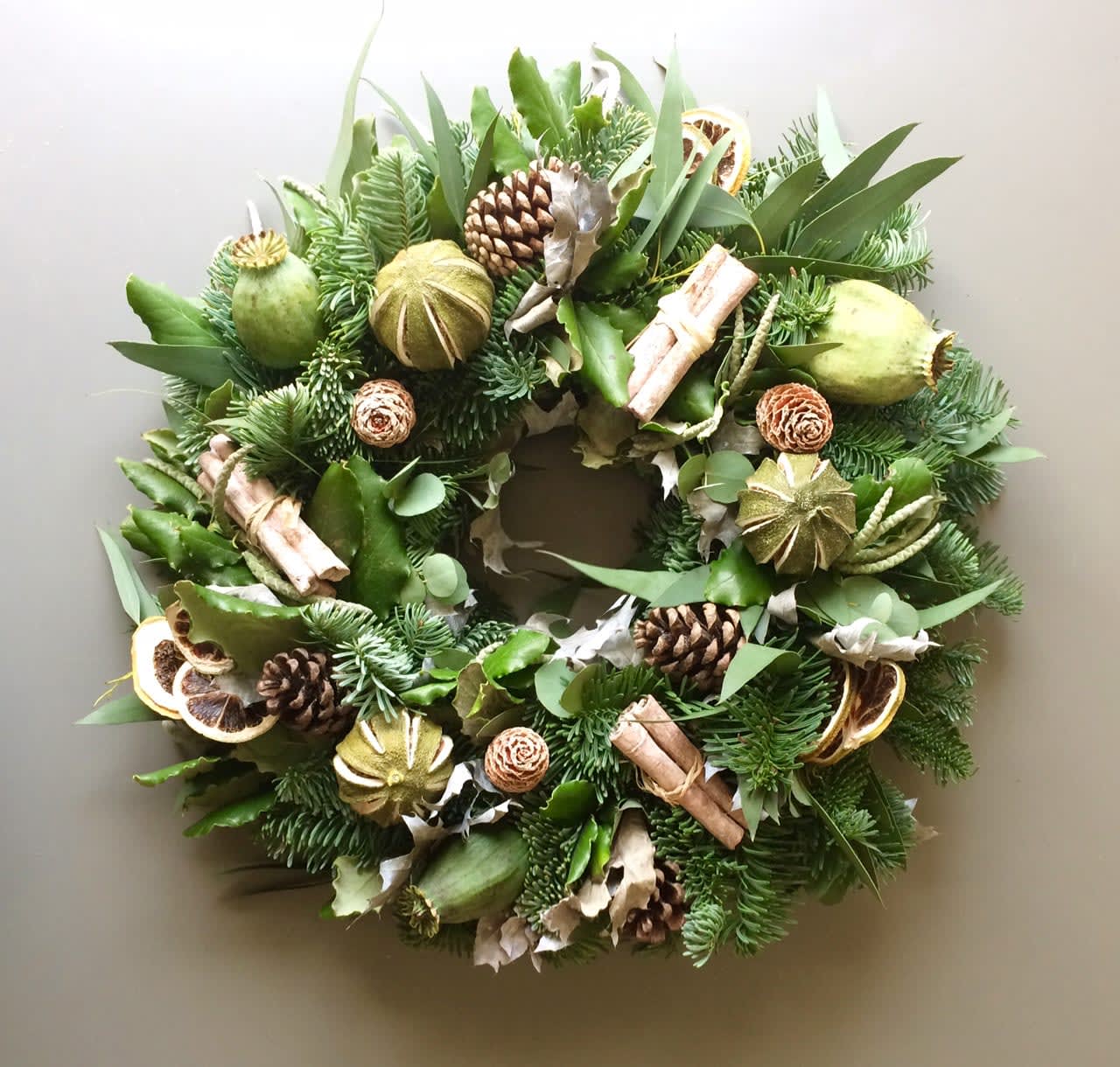 Green holiday wreath with pinecones, dried citrus, and cinnamon sticks
