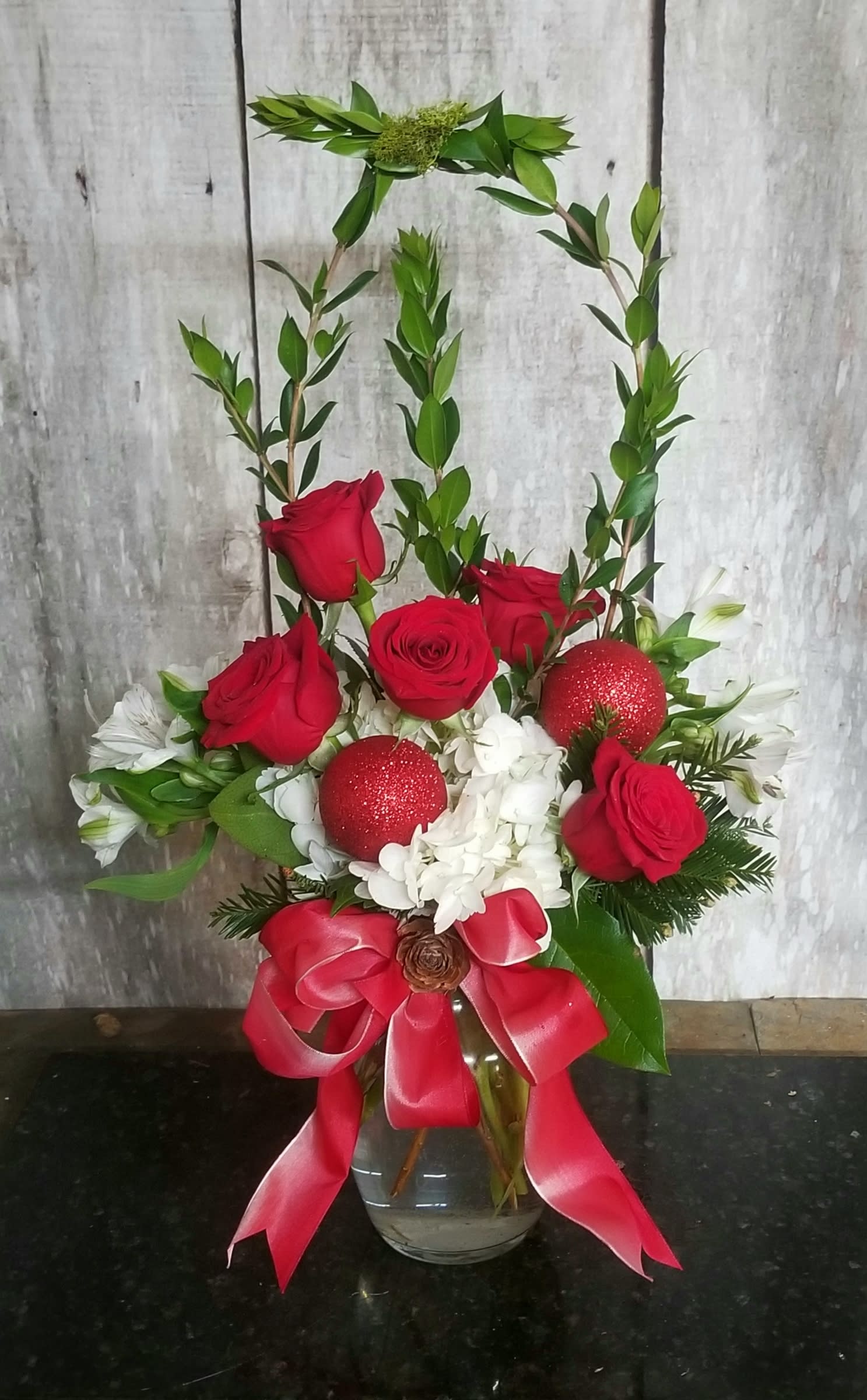 Red roses and white flowers in a glass vase with a red ribbon