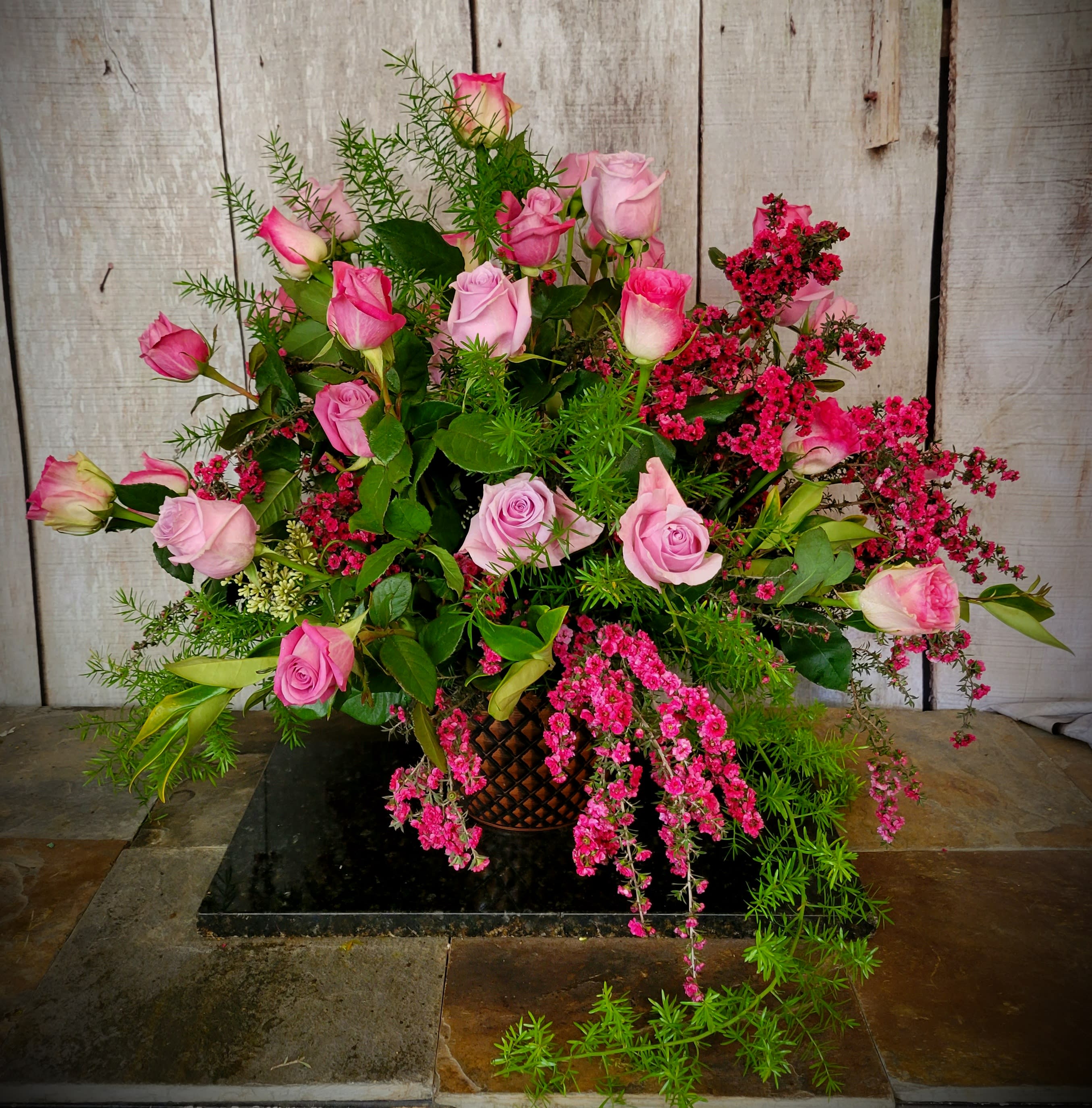 Pink roses arranged in a basket with trailing pink filler flowers