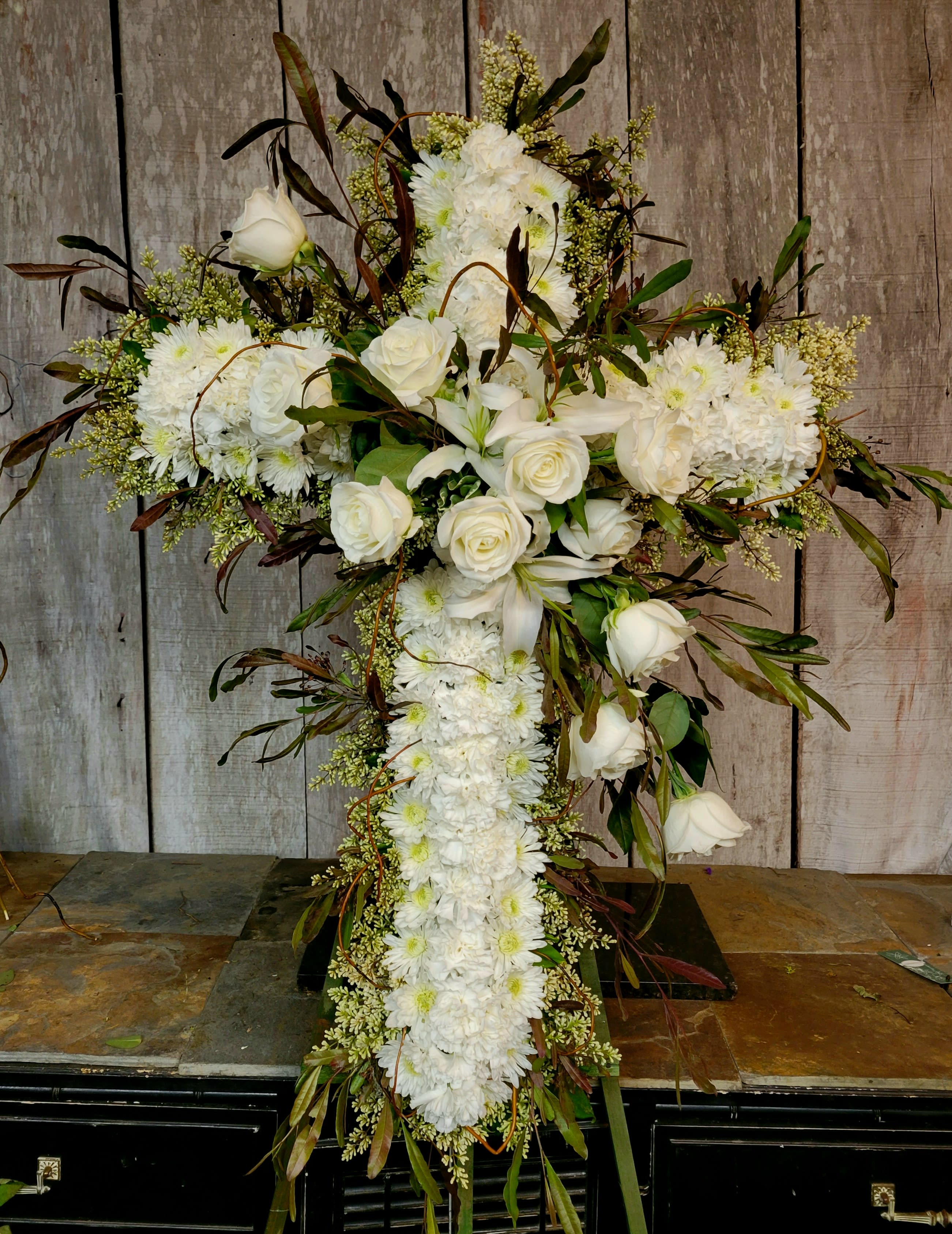 White floral cross arrangement with roses and daisies
