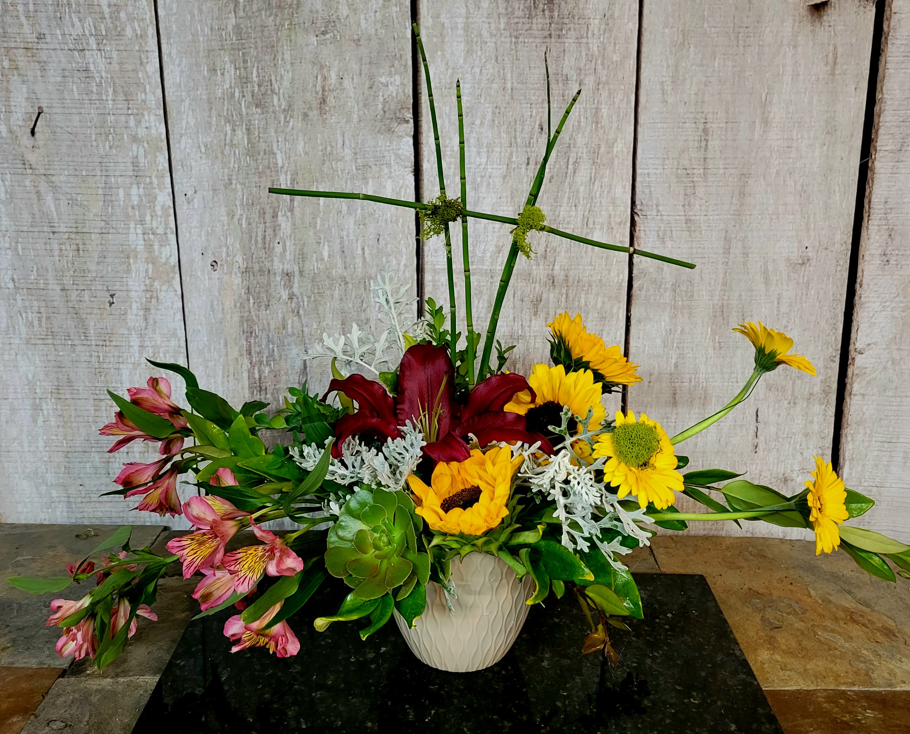 Mixed floral arrangement in a white vase with lilies and sunflowers