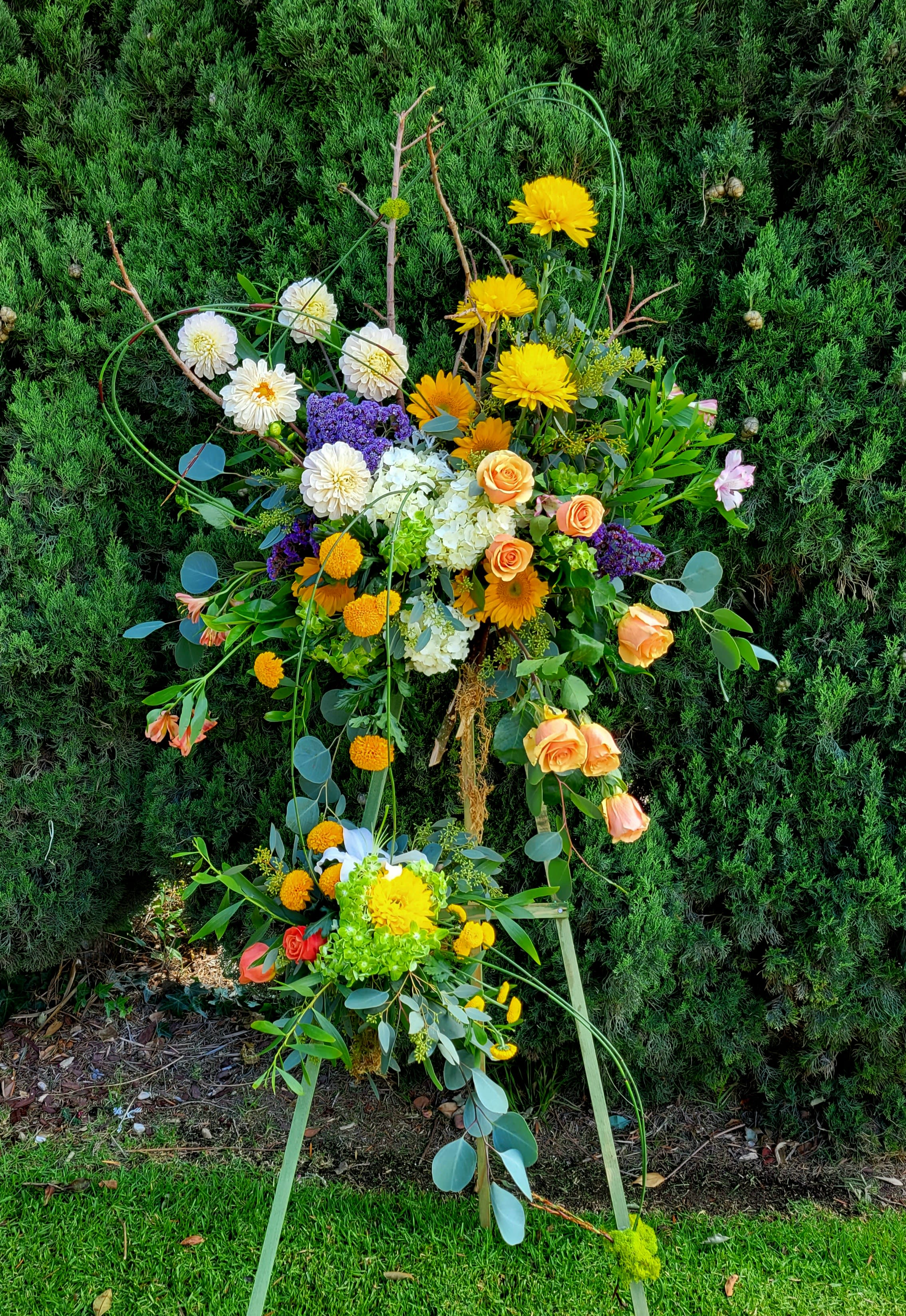 Large floral standing spray with yellow, white, orange, and purple blooms