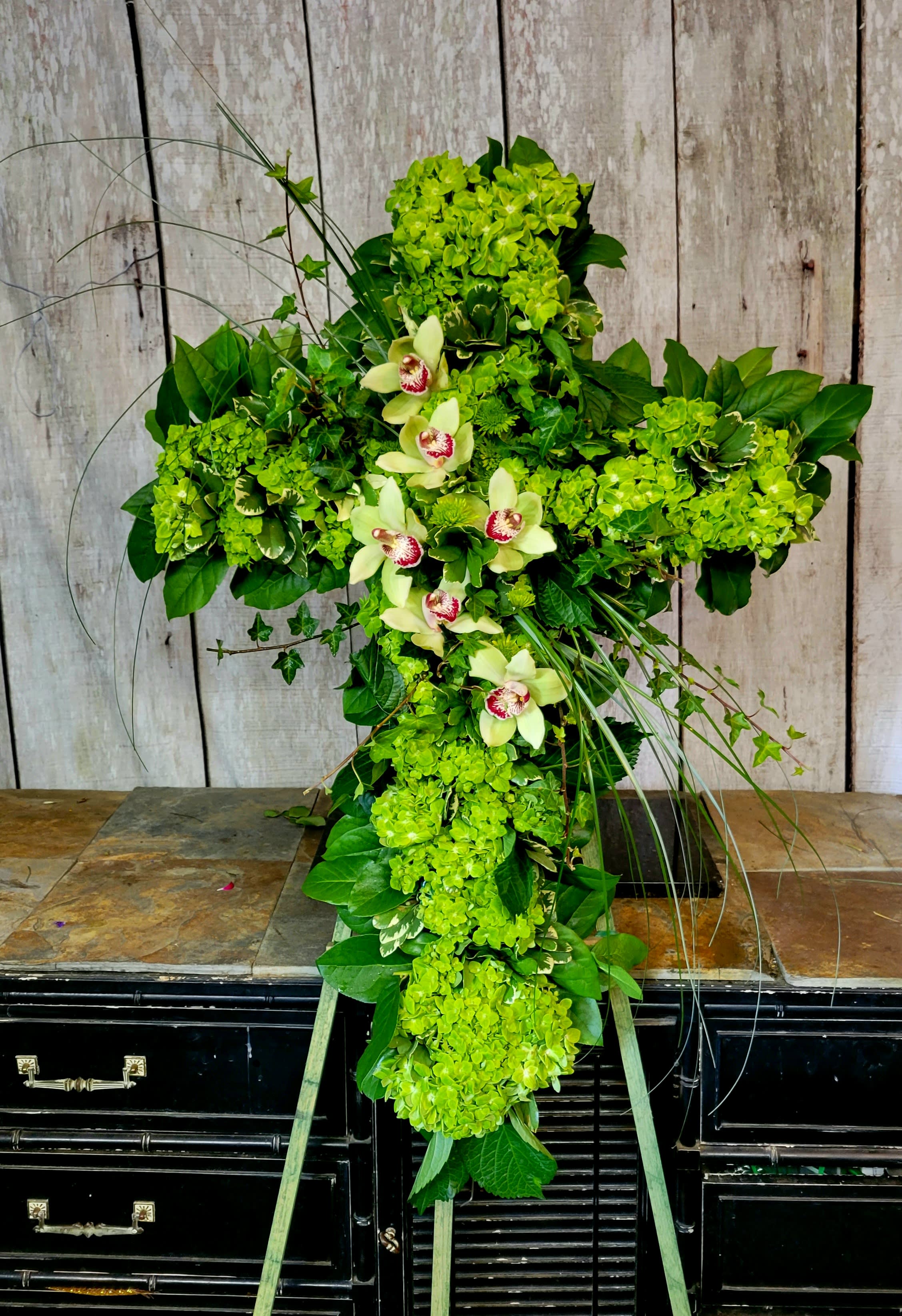 Green floral cross with orchids and hydrangeas on a stand