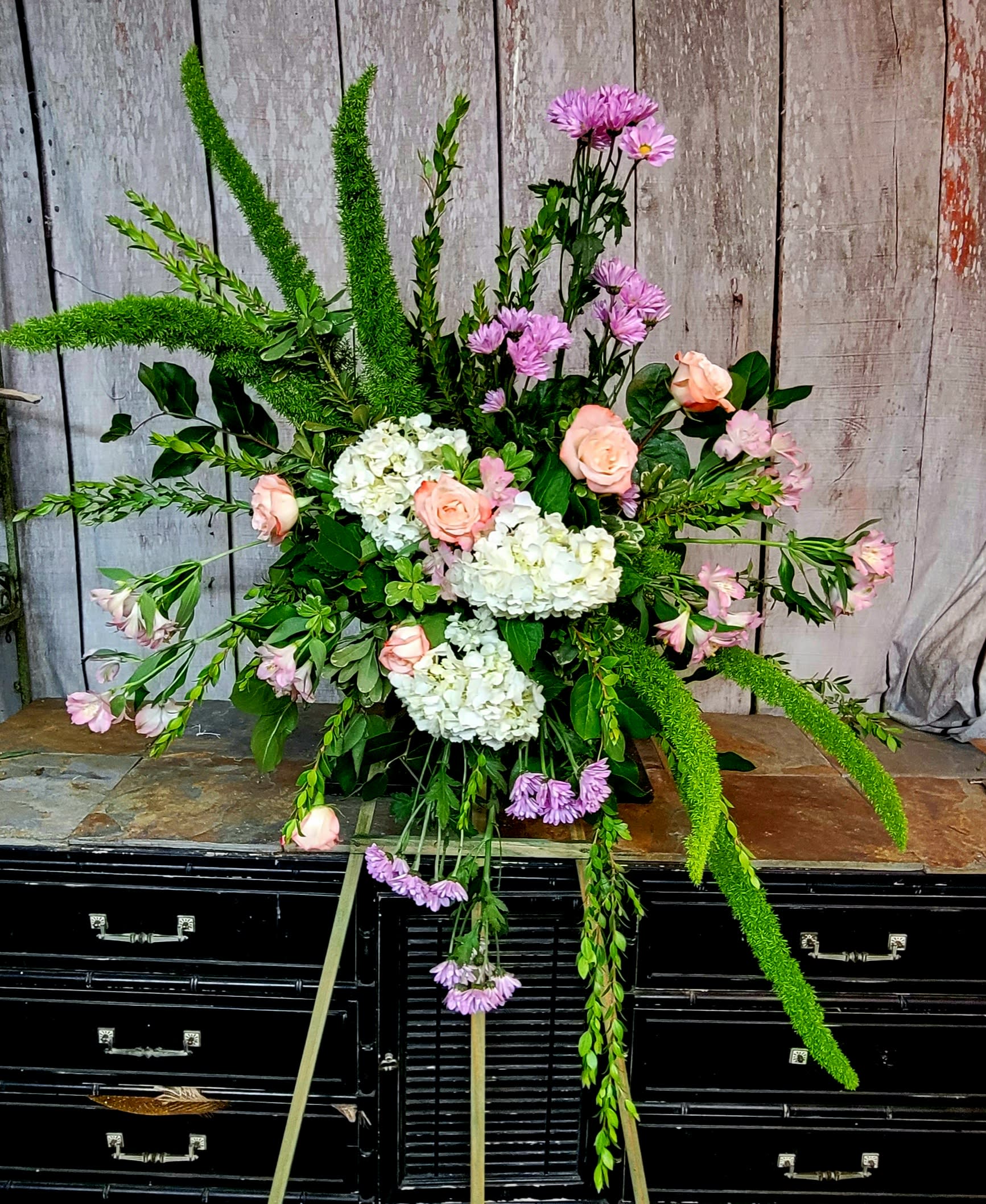 Large floral spray with pink roses, white hydrangeas, and purple blooms