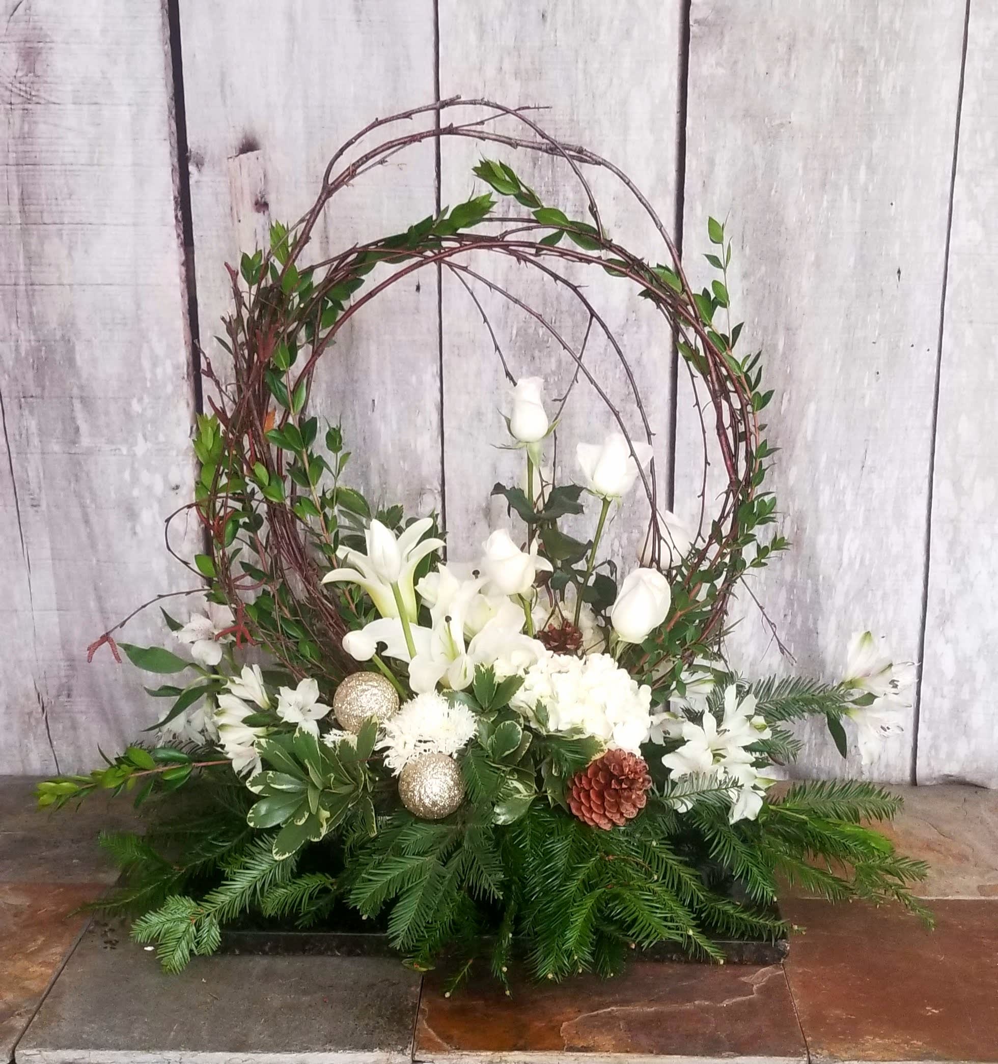 White floral arrangement with a twig wreath and evergreen base