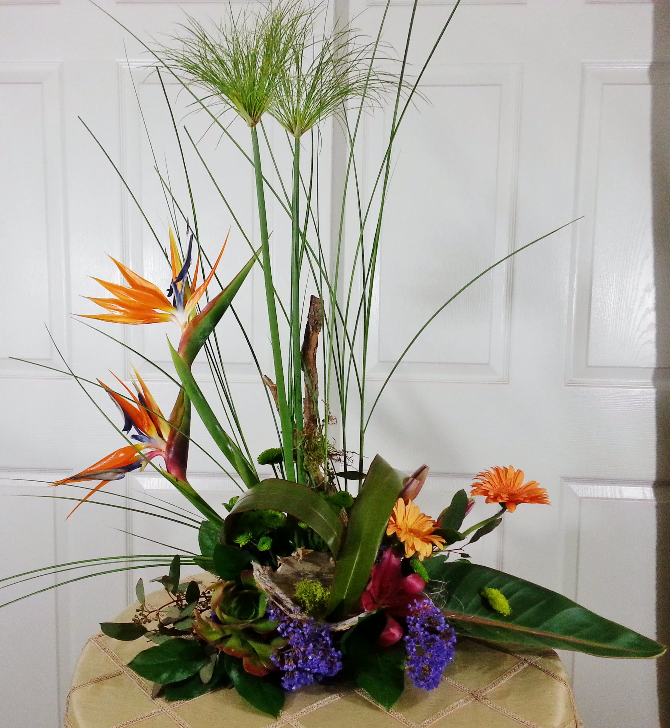 Tall tropical arrangement with orange bird-of-paradise and purple accents