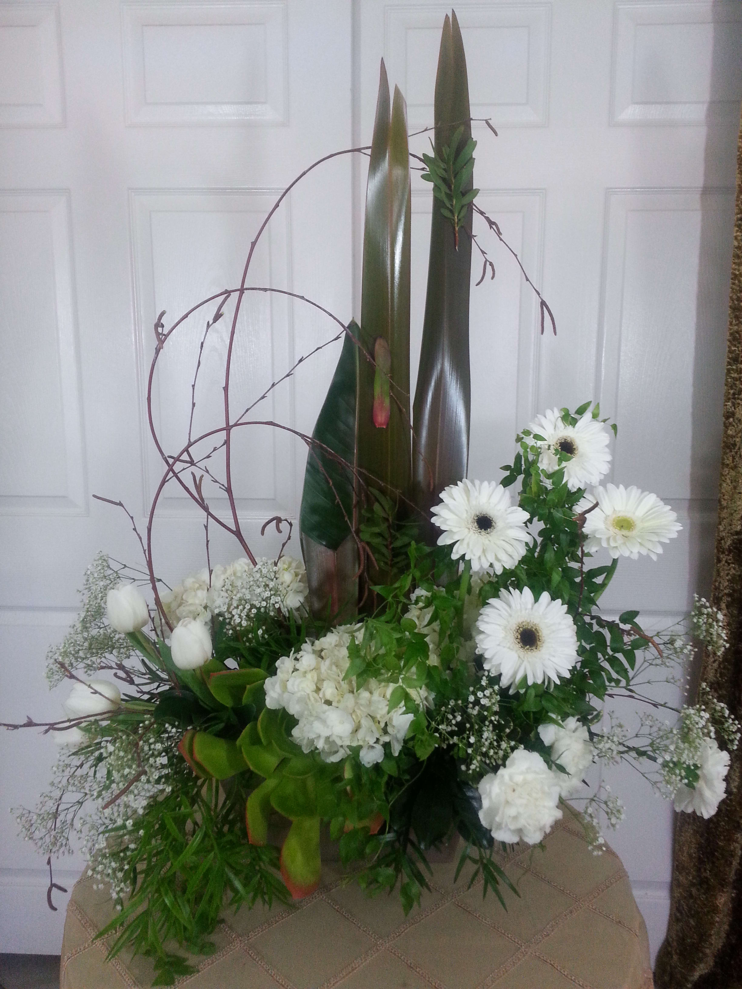Tall white floral arrangement with gerbera daisies and tulips