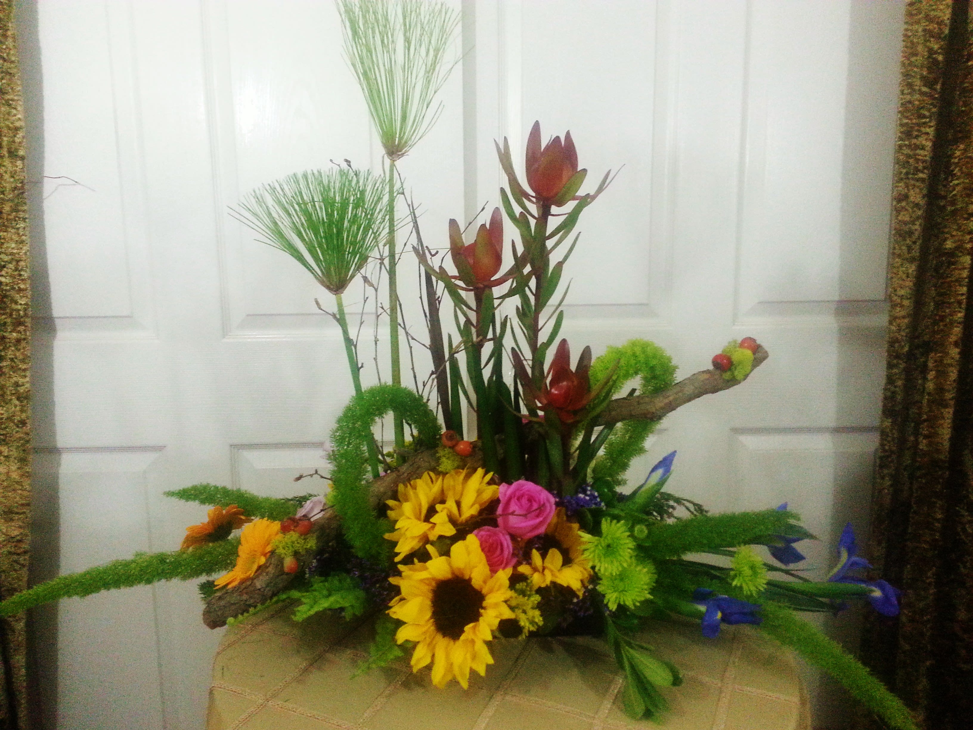 Colorful floral arrangement with sunflowers, pink roses, and tall tropical blooms