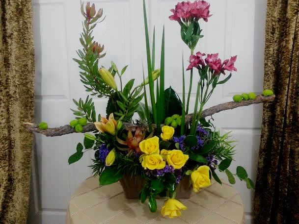Tall floral arrangement with yellow roses and pink lilies in a container