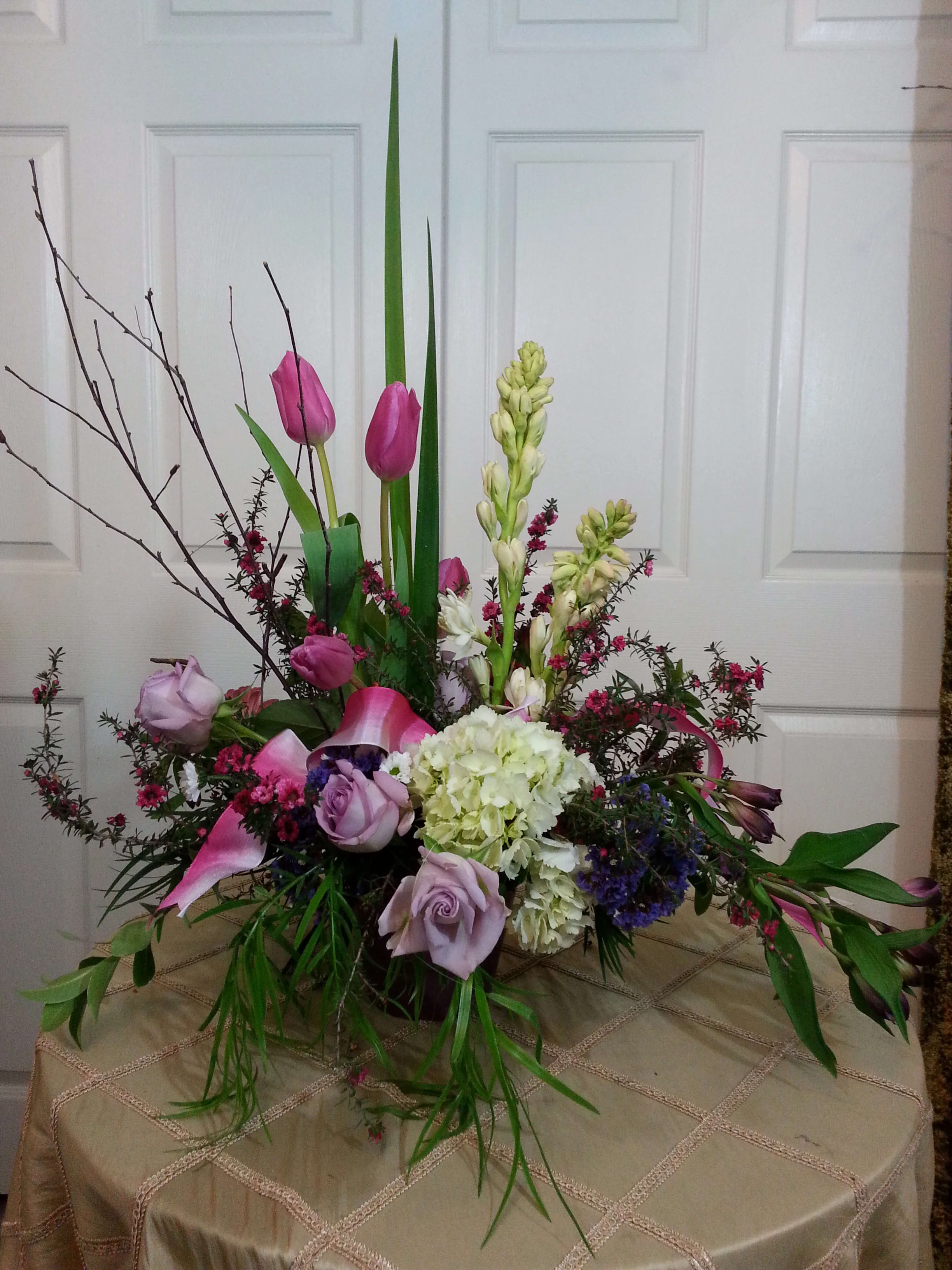 Tall floral arrangement with pink tulips, lavender roses, and white hydrangea