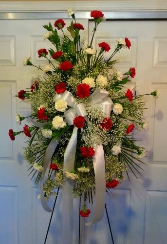 Standing floral spray with red and white carnations and white ribbon