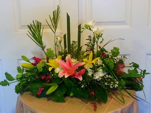 Low floral centerpiece with lilies and mixed blooms in a shallow container