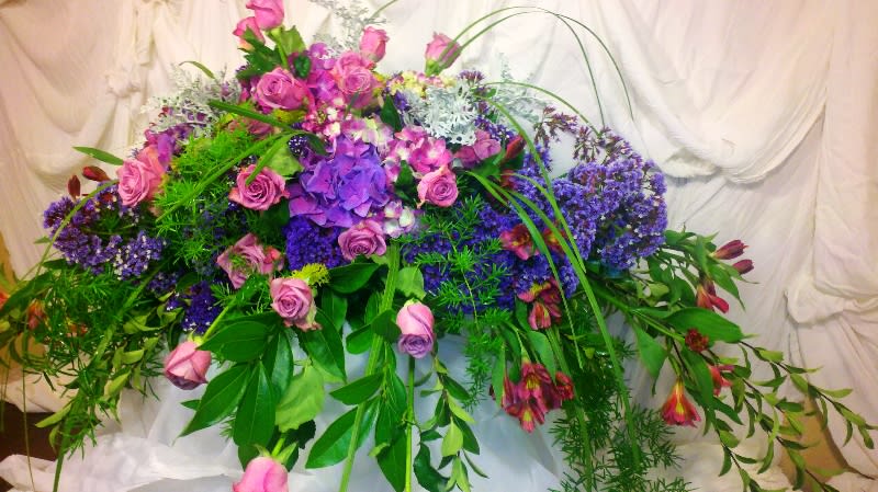 Large arrangement of pink and purple flowers with cascading greenery