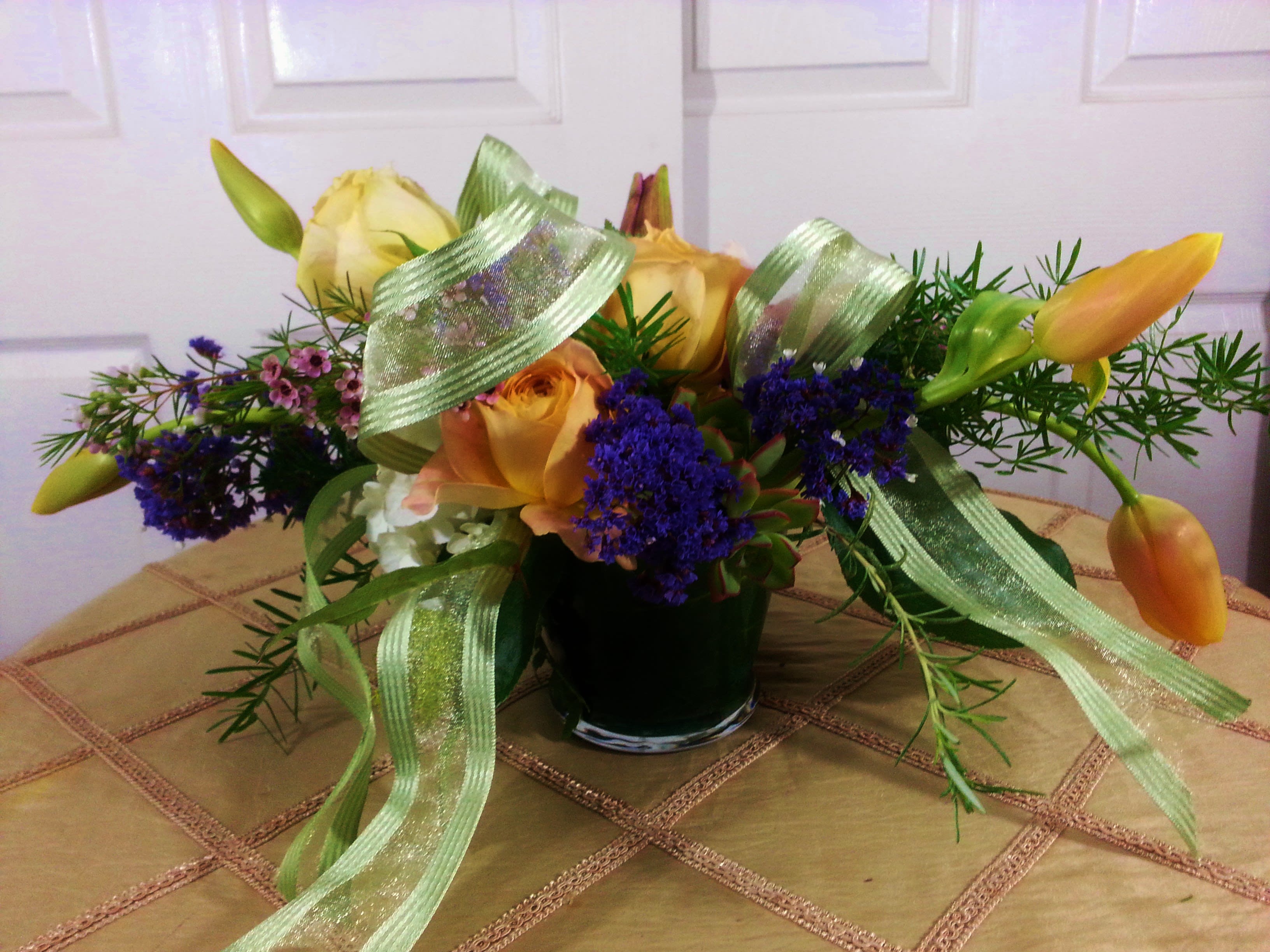 Bouquet of yellow roses and orange tulips in a glass vase with ribbon