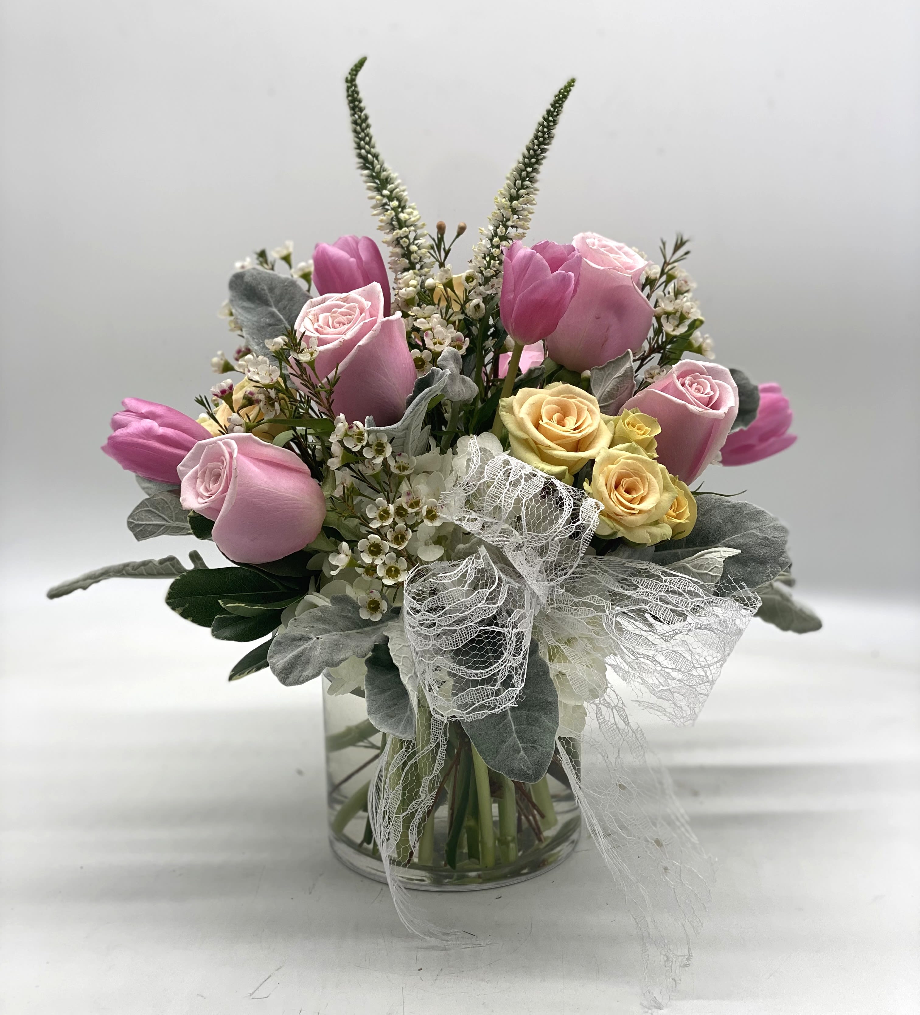 Pink and yellow roses with tulips in a glass vase