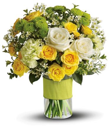 Yellow and white roses in a glass vase with green blooms