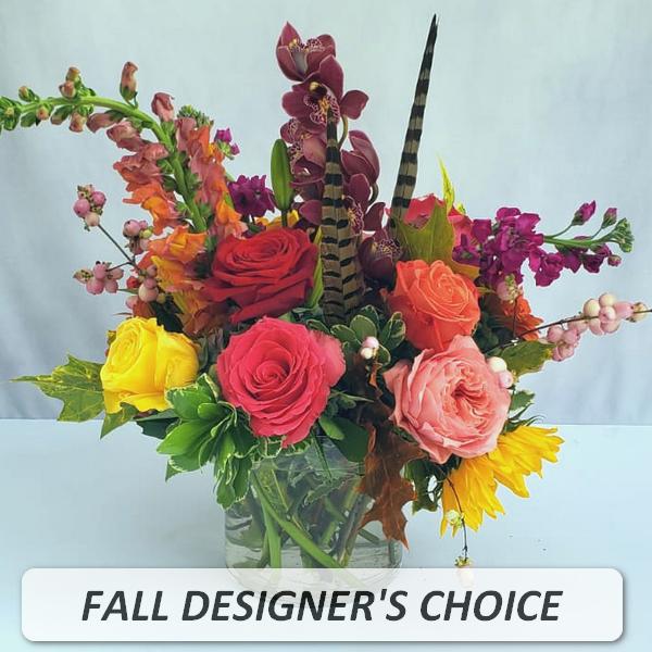 Mixed fall flower arrangement with roses, orchids, sunflowers and snapdragons in a clear glass vase