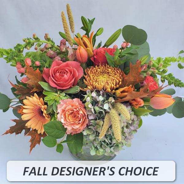 Round fall arrangement with orange roses, gerberas, and mums in a clear glass vase