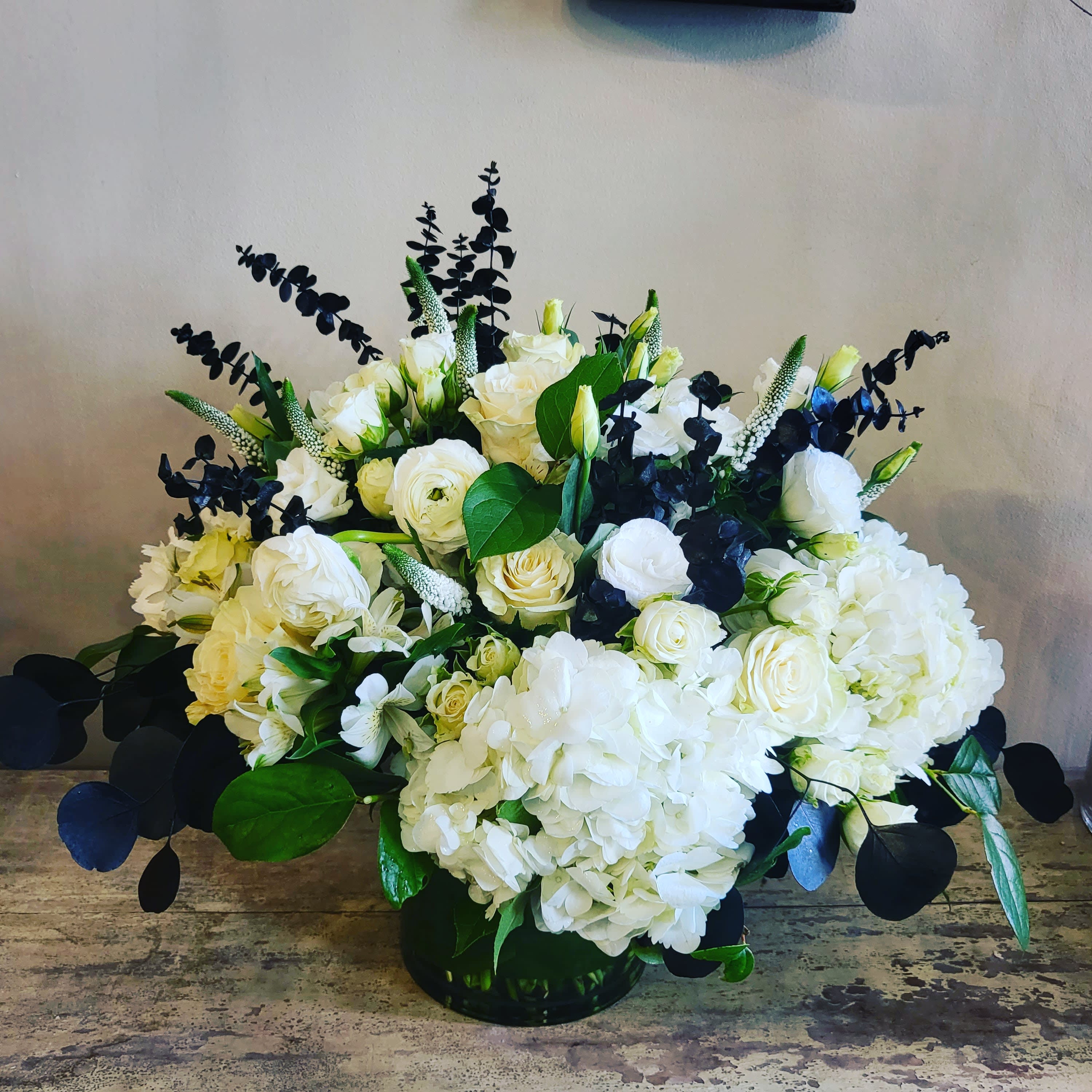 White rose and hydrangea arrangement in a low black vase