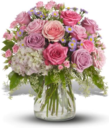 Pink and lavender roses in a glass vase with small purple daisies