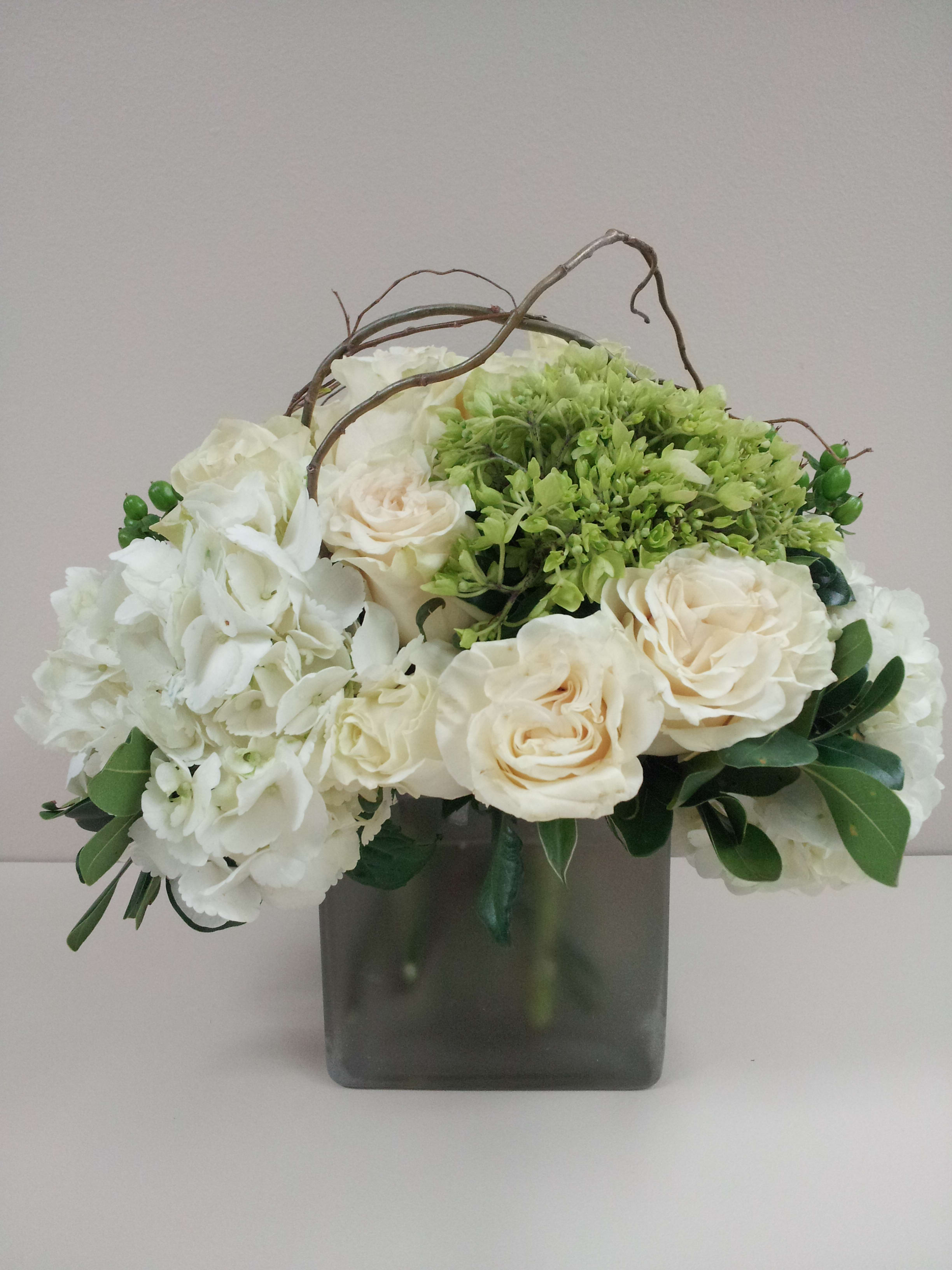 White and cream roses with green hydrangea in a square glass vase