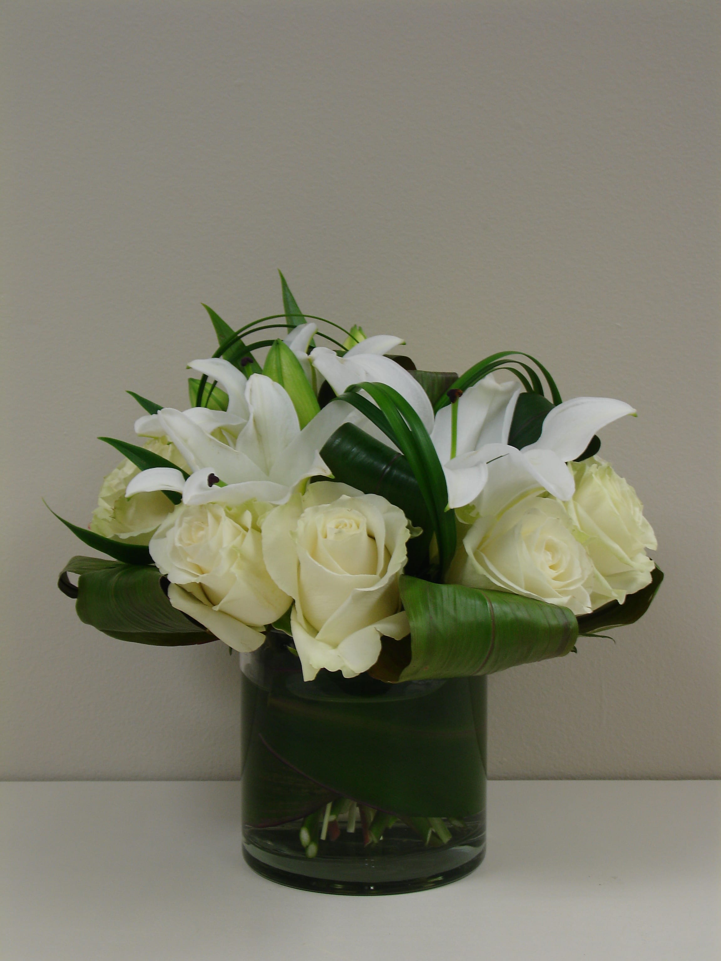 White roses and lilies arranged in a glass vase