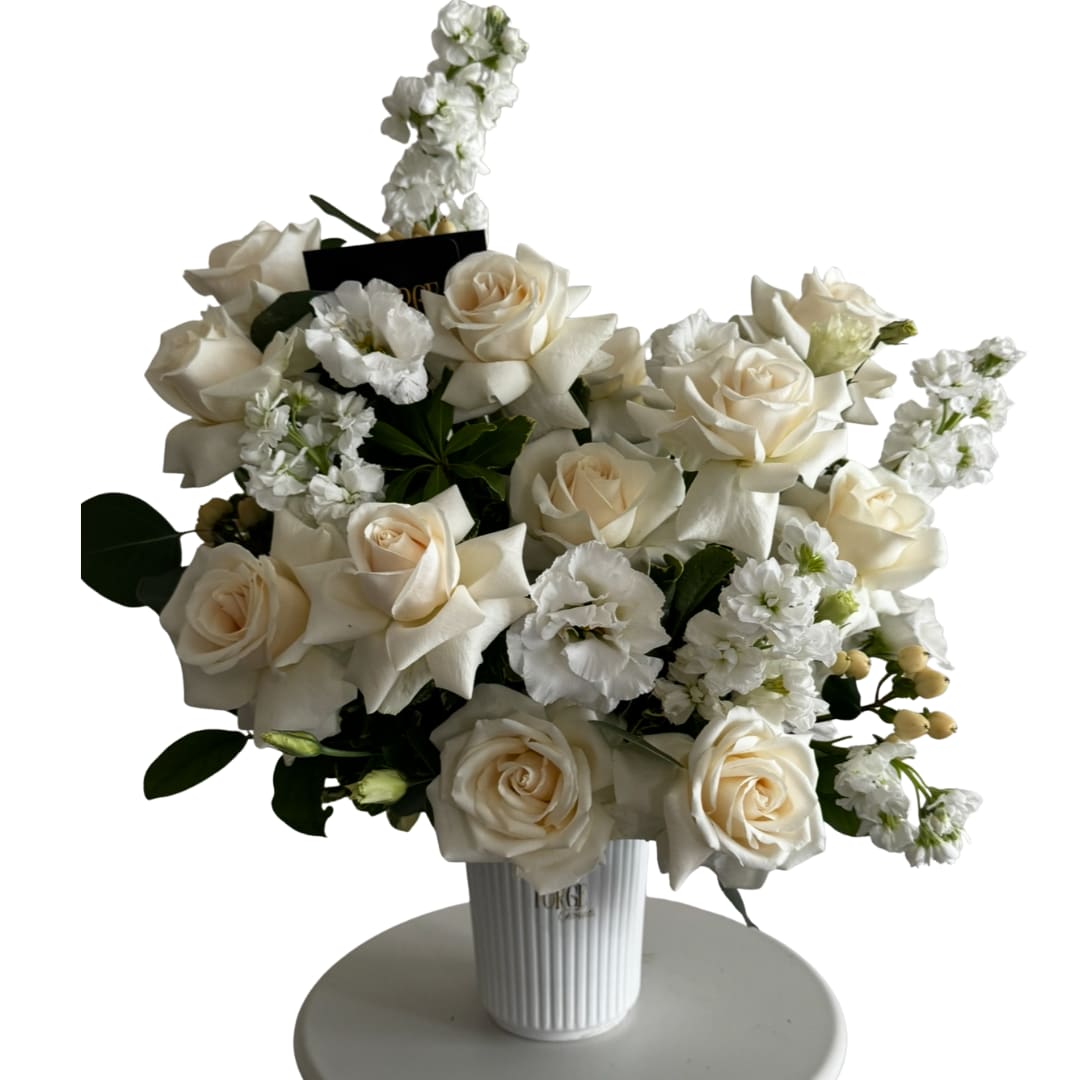 White rose arrangement in a ribbed vase with small white accent flowers