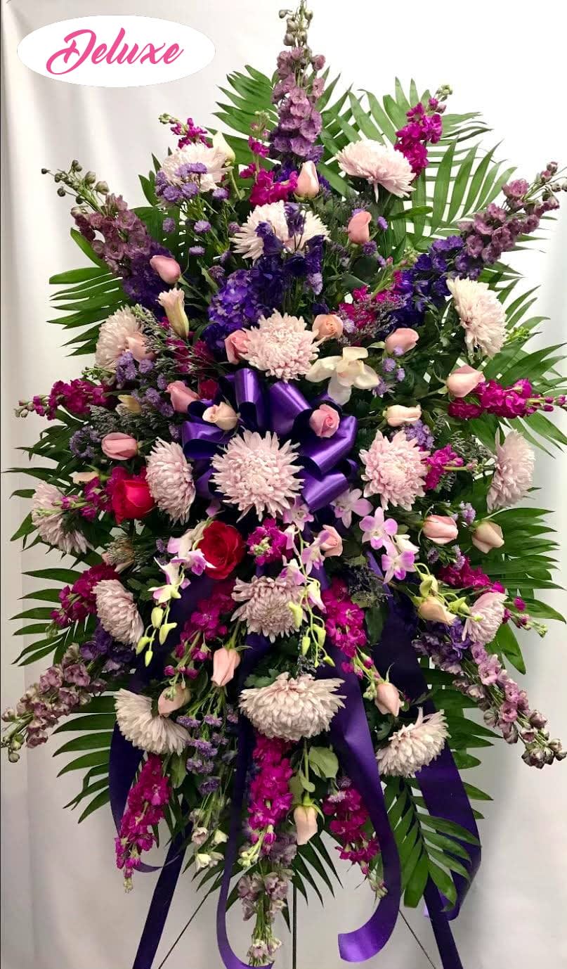 Large standing floral spray with purple and pink flowers and ribbon
